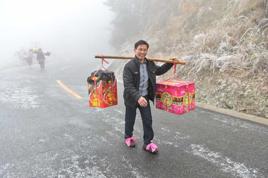 Local people hike home carrying various festival foods for the upcoming Lunar New Year on the slick highway after an ice storm in Leishan county, Qiandongnan Miao and Dong autonomous prefecture, in Guizhou province. Chen Peiliang / China Daily