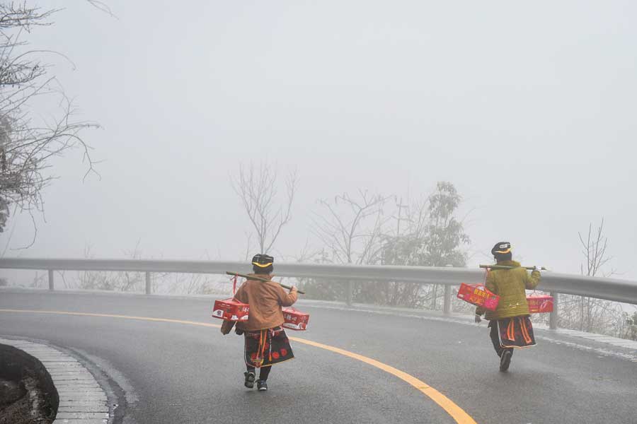 Local people hike home carrying various festival foods for the upcoming Lunar New Year on the slick highway after an ice storm in Leishan county, Qiandongnan Miao and Dong autonomous prefecture, in Guizhou province. Chen Peiliang / China Daily