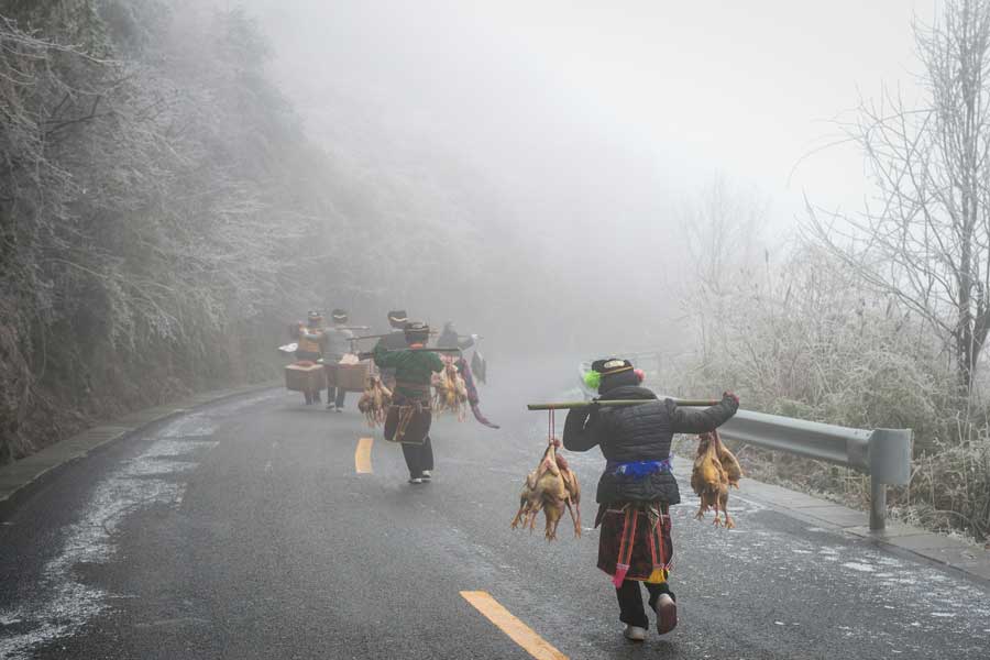 Local people hike home carrying various festival foods for the upcoming Lunar New Year on the slick highway after an ice storm in Leishan county, Qiandongnan Miao and Dong autonomous prefecture, in Guizhou province. Chen Peiliang / China Daily