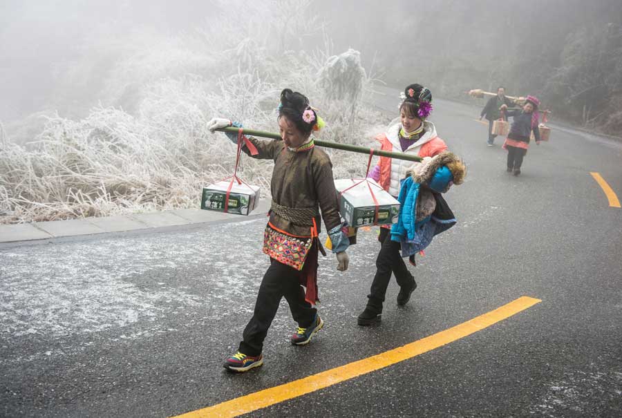 Local people hike home carrying various festival foods for the upcoming Lunar New Year on the slick highway after an ice storm in Leishan county, Qiandongnan Miao and Dong autonomous prefecture, in Guizhou province. Chen Peiliang / China Daily 