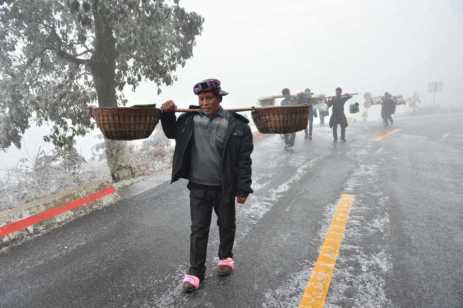 Local people hike home carrying various festival foods for the upcoming Lunar New Year on the slick highway after an ice storm in Leishan county, Qiandongnan Miao and Dong autonomous prefecture, in Guizhou province. Chen Peiliang / China Daily