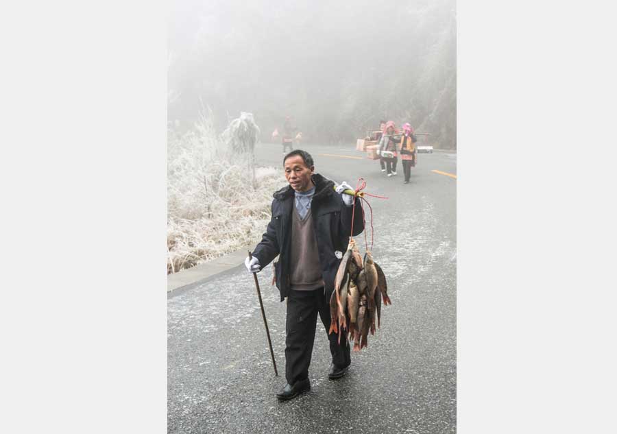 Local people hike home carrying various festival foods for the upcoming Lunar New Year on the slick highway after an ice storm in Leishan county, Qiandongnan Miao and Dong autonomous prefecture, in Guizhou province. Chen Peiliang / China Daily