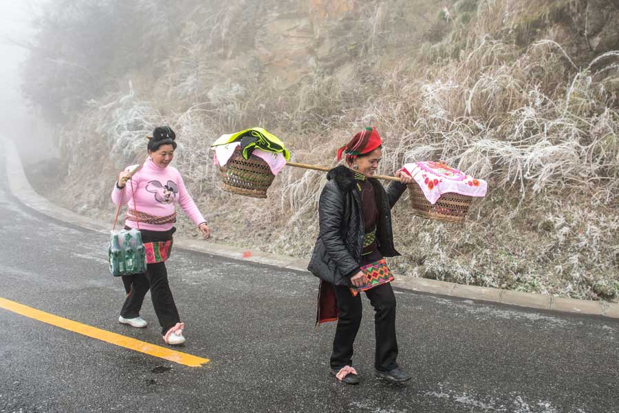 Local people hike home carrying various festival foods for the upcoming Lunar New Year on the slick highway after an ice storm in Leishan county, Qiandongnan Miao and Dong autonomous prefecture, in Guizhou province. Chen Peiliang / China Daily