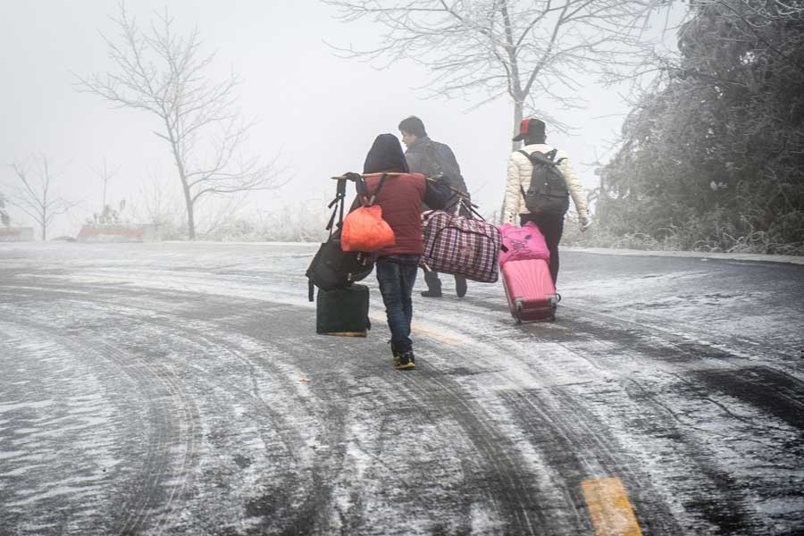 Local people hike home carrying various festival foods for the upcoming Lunar New Year on the slick highway after an ice storm in Leishan county, Qiandongnan Miao and Dong autonomous prefecture, in Guizhou province. Chen Peiliang / China Daily