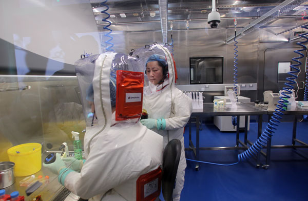 Scientists wearing protective clothing work in the experiment zone at China's first P4 laboratory in Wuhan, Hubei province, on Saturday. Anyone entering the facility has to have undertaken rigorous training to ensure safety and security. Zou Hong / China Daily 
