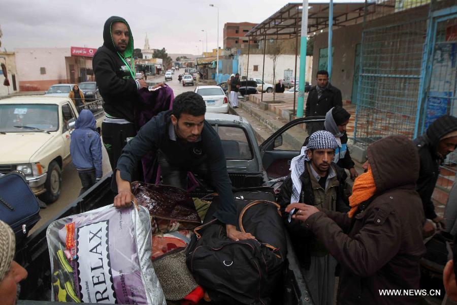 Egyptian men load their luggage as boarding a bus back home in Salloum, Egypt, east of the border with Libya, on Feb. 19, 2015. Over 6,000 Egyptians have returned from Libya, since the air strike against the Islamic State (IS) in the neighboring country on Monday, according to Salloum land port gate authority. [Photo/Xinhua]