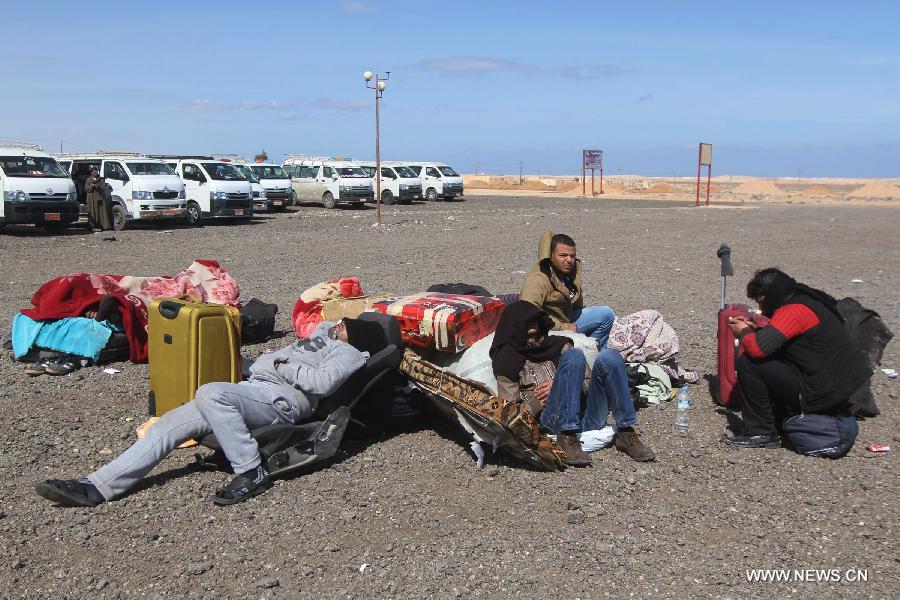 Egyptian men wait to board buses back home in Salloum, Egypt, east of the border with Libya, on Feb. 21, 2015. Over 6,000 Egyptians have returned from Libya, since the air strike against the Islamic State (IS) in the neighboring country on Monday, according to Salloum land port gate authority. [Photo/Xinhua]