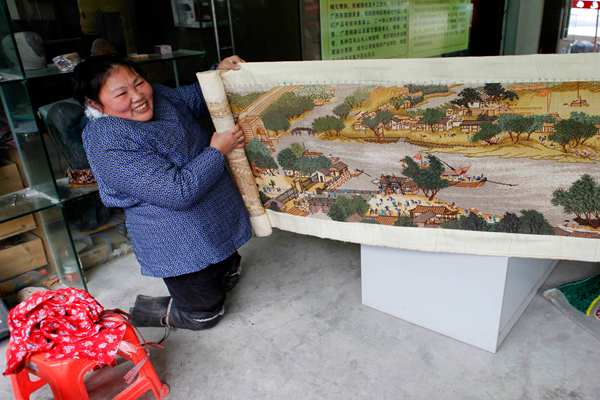 Hu Fenglian displays an embroidery painting she made. [Huo Yan/China Daily]