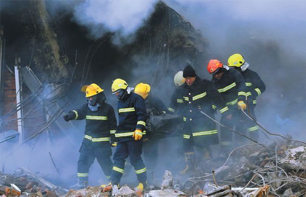 Firefighters carry the body of a dead colleague on a stretcher after a warehouse fire in the northeastern city of Harbin in Heilongjiang province in January. Five firefighters died fighting the blaze and 14 people were injured. Xiao Jingbiao / For China Daily