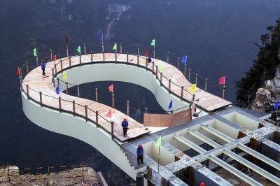 Workers stand on the cantilever bridge at Longgang scenic area in Yunyang, southwest China's Chongqing municipality.[Photo/Xinhua]