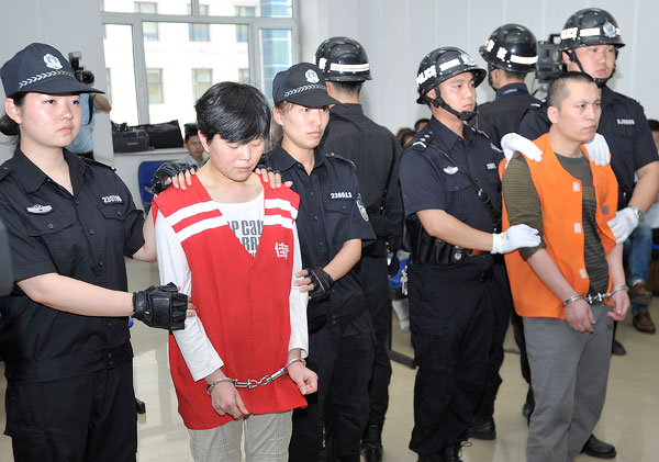 Two suspects on prison uniforms stand on trial in this 2014 file photo. The outfits may not be seen in the court in the future because a new rule by the Supreme People's Court will forbid suspects on trial wearing clothes that may influence opinion on their guilt. [Photo by Xiao Jinbiao/China Daily] 