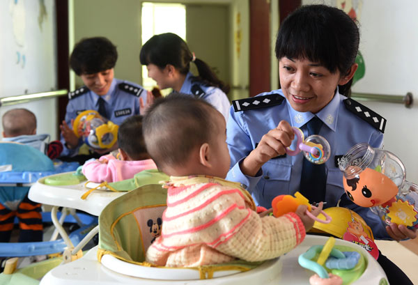 Police officers visit babies, rescued from kidnappers, at an orphanage in Kunming, Yunnan province. Kunming police saved 11 babies after breaking up a gang of kidnappers that targeted babies in November. LIN YIGUANG/XINHUA