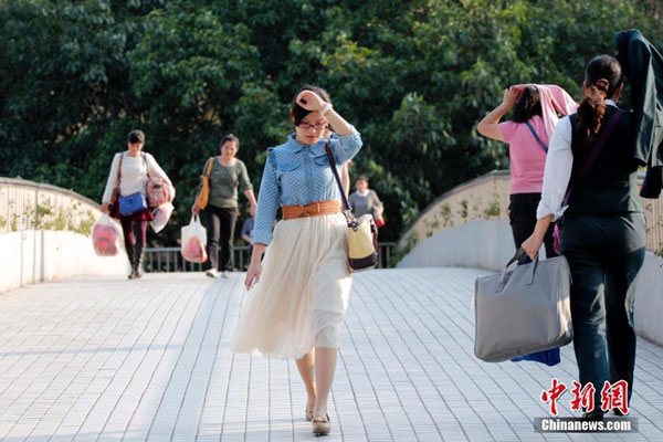 A pedestrian holds her arm against the glaring sunshine in Nanning, South China's Guangxi Zhuang autonomous region. The area's hot weather season starts ahead of most cities in China, with its temperature reaching 30 degrees Celsius on Thursday. [Photo/chinanews.com] 