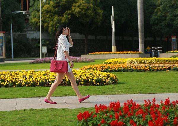 A young woman walks in summer clothes. [Photo/chinanews.com]