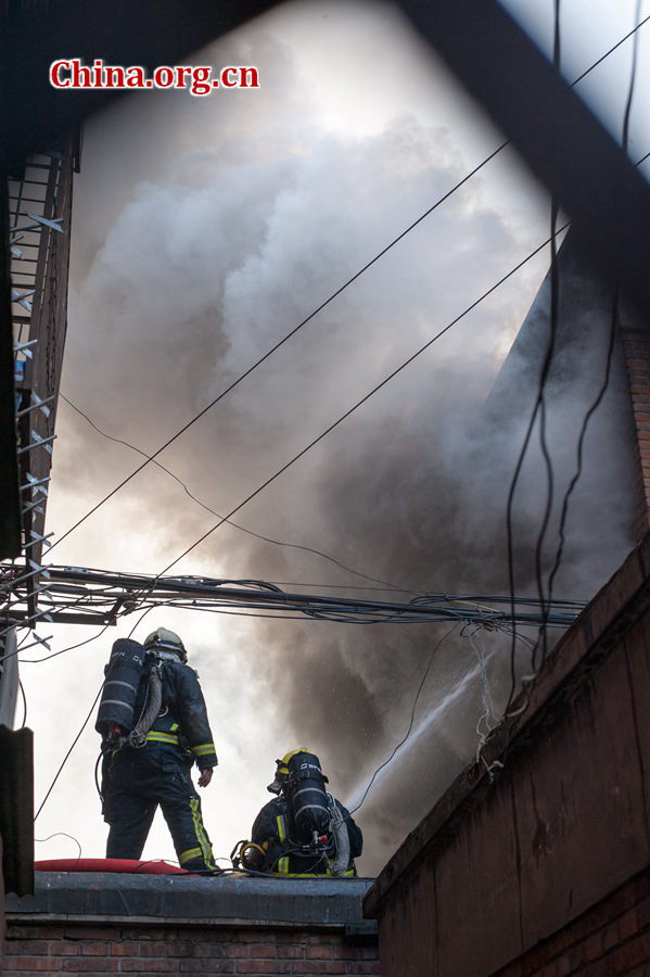 Firefighters pump water into a blazing building in a residential area in downtown Beijing on Thursday, March 5, the traditional Chinese Lantern Festival. The building located between Linglong Rd. and Qixiancun Rd. in Haidian District, is used as a warehouse of Gehua, Beijing&apos;s local cable TV service provider. The burning rubber from the cable wire gives out a strong black smoke. [Photo by Chen Boyuan / China.org.cn]