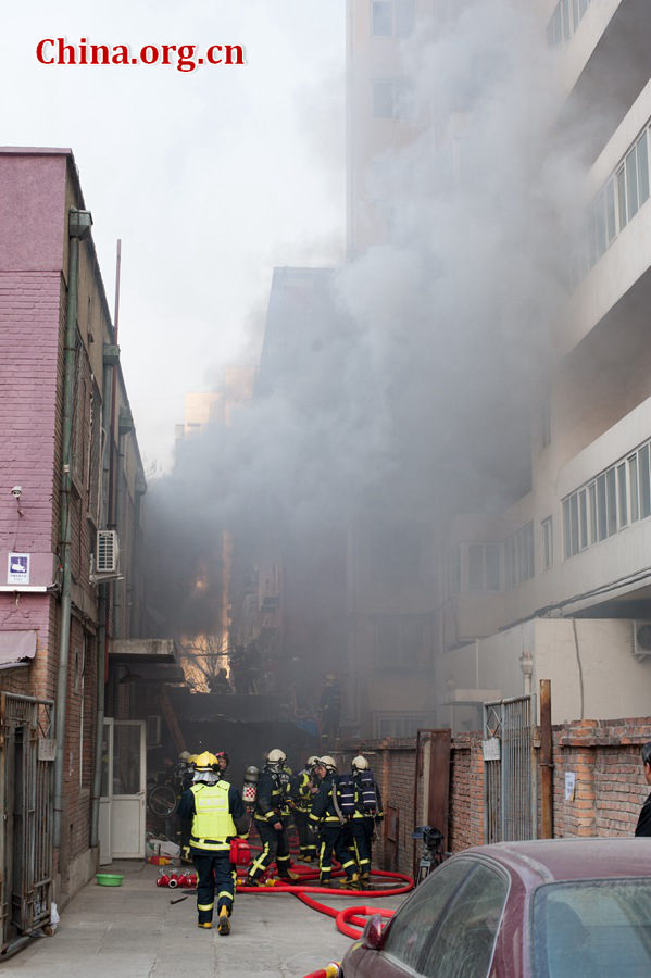 Firefighters pump water into a blazing building in a residential area in downtown Beijing on Thursday, March 5, the traditional Chinese Lantern Festival. The building located between Linglong Rd. and Qixiancun Rd. in Haidian District, is used as a warehouse of Gehua, Beijing&apos;s local cable TV service provider. The burning rubber from the cable wire gives out a strong black smoke. [Photo by Chen Boyuan / China.org.cn]