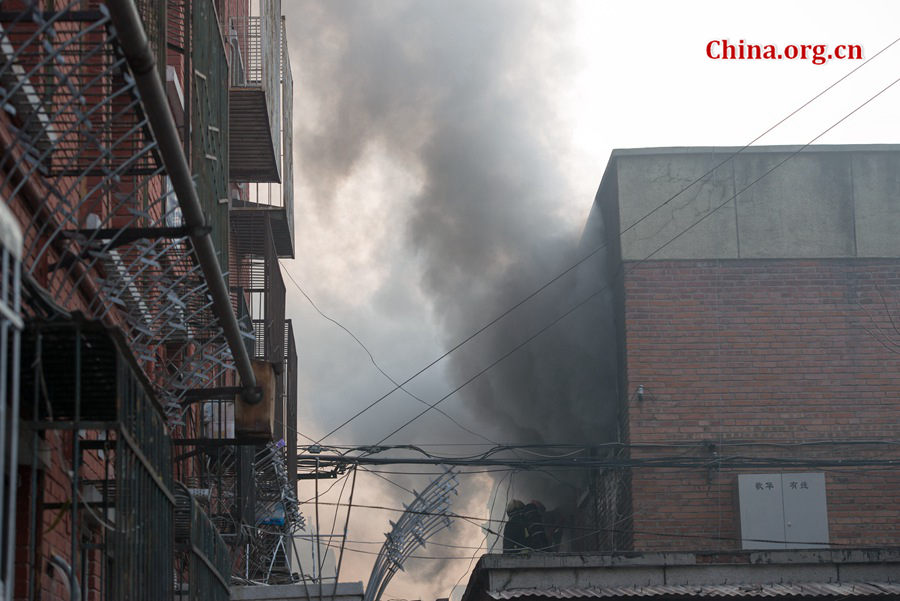 Firefighters pump water into a blazing building in a residential area in downtown Beijing on Thursday, March 5, the traditional Chinese Lantern Festival. The building located between Linglong Rd. and Qixiancun Rd. in Haidian District, is used as a warehouse of Gehua, Beijing&apos;s local cable TV service provider. The burning rubber from the cable wire gives out a strong black smoke. [Photo by Chen Boyuan / China.org.cn]