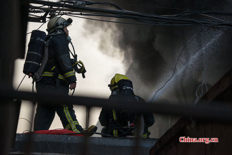 Firefighters pump water into a blazing building on Thursday, March 5, the traditional Chinese Lantern Festival. The building, according to people who live nearby, is used as a warehouse of Gehua, Beijing&apos;s local cable TV service provider, and the burning rubber from the cable gives out a strong black smoke. [Photo by Chen Boyuan / China.org.cn]