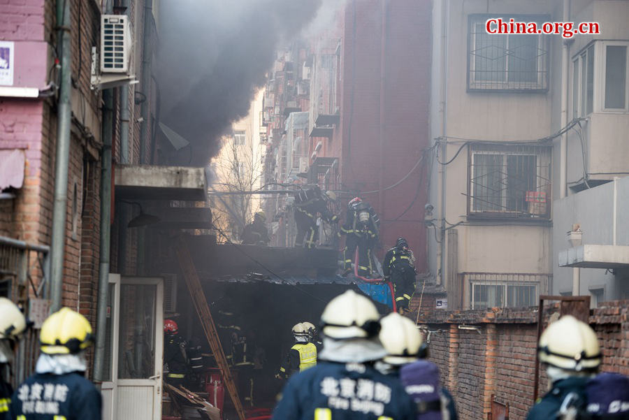 Firefighters pump water into a blazing building in a residential area in downtown Beijing on Thursday, March 5, the traditional Chinese Lantern Festival. The building located between Linglong Rd. and Qixiancun Rd. in Haidian District, is used as a warehouse of Gehua, Beijing&apos;s local cable TV service provider. The burning rubber from the cable wire gives out a strong black smoke. [Photo by Chen Boyuan / China.org.cn]