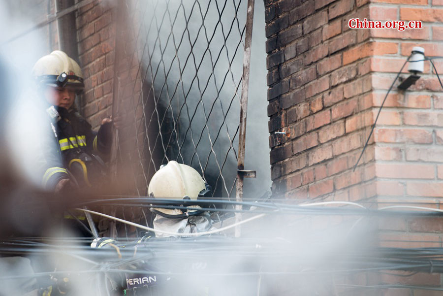 Firefighters try to break into a blazing building in a residential area in downtown Beijing on Thursday, March 5, the traditional Chinese Lantern Festival. The building is located between Linglong Rd. and Qixiancun Rd. in Haidian District, is used as a warehouse of Gehua, Beijing&apos;s local cable TV service provider. The burning rubber from the cable wire gives out a strong black smoke. [Photo by Chen Boyuan / China.org.cn]