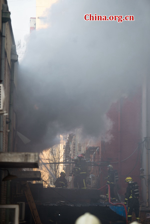 Firefighters pump water into a blazing building in a residential area in downtown Beijing on Thursday, March 5, the traditional Chinese Lantern Festival. The building located between Linglong Rd. and Qixiancun Rd. in Haidian District, is used as a warehouse of Gehua, Beijing&apos;s local cable TV service provider. The burning rubber from the cable wire gives out a strong black smoke. [Photo by Chen Boyuan / China.org.cn]