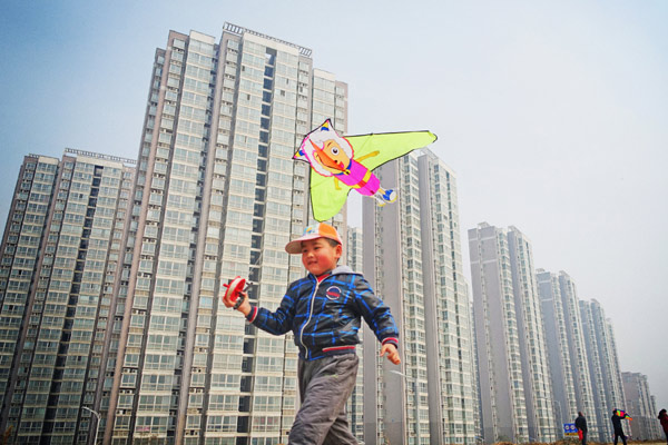 A boy flies a kite beside a massive residential project in Luoyang, Henan province, on March 8. Many local governments have ramped up efforts to bolster home sales after the moves to ease purchase restrictions barely worked. [Huang Zhengwei / For China Daily]