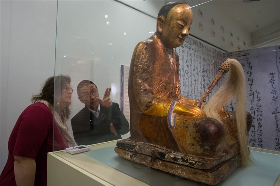 Two experts examine a Buddha statue containing the preserved remains (inset) of a 1,000-year-old monk in the Hungarian Natural History Museum. The museum pulled it from an exhibition on Friday. Chinese experts have said that the statue was stolen from a Chinese village in 1995. — Xinhua