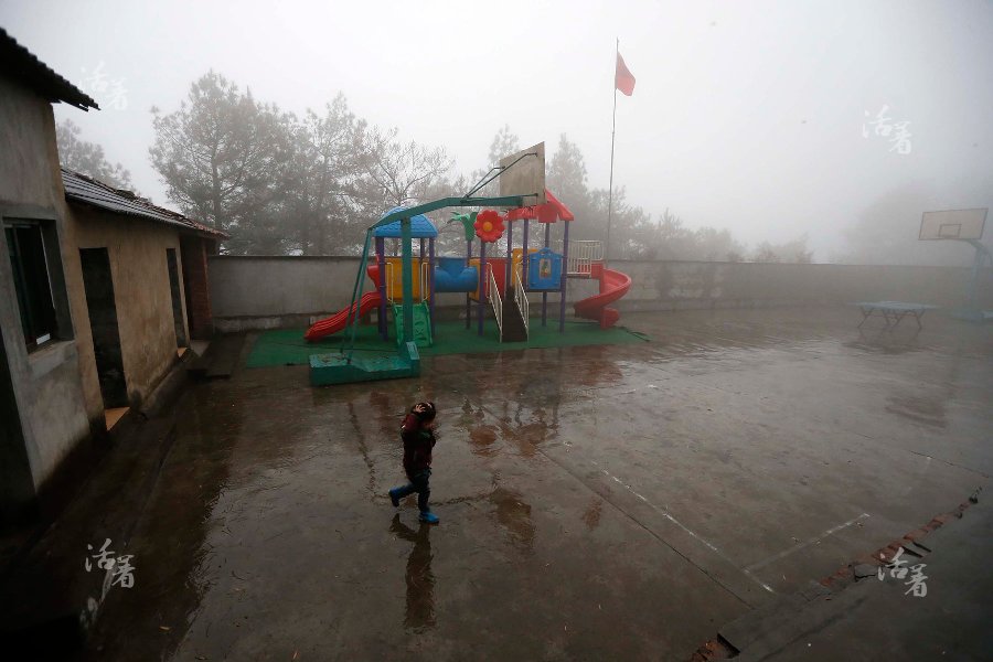 Using his hands to keep off the rain, a child runs to the classroom in the cold winter rain at Dalishan elementary school in Longyou County of Zhejiang province. [Photo/qq.com] 