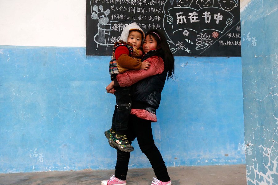  An older student carries Li Feifan in front of a blackboard during a class break. [Photo/qq.com]