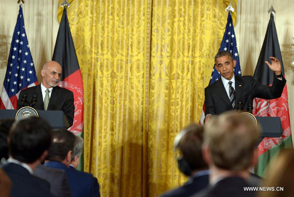 U.S. President Barack Obama(R) speaks as Afghan President Ashraf Ghani listens during a joint press conference in the East Room of White House in Washington D.C., the United States, March 24, 2015. U.S. President Barack Obama announced Tuesday no drawdown of the current 9,800 U.S. troops stationed in Afghanistan will occur through the end of 2015.