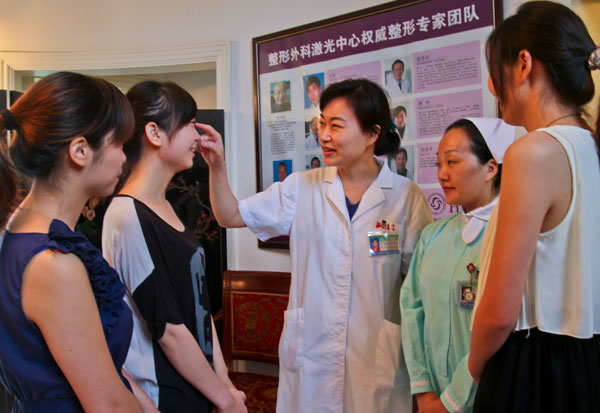 A plastic surgeon talks with high school students who are considering plastic surgery at the People's Liberation Army No 455 Hospital in Shanghai in August. [Photo/China Daily]