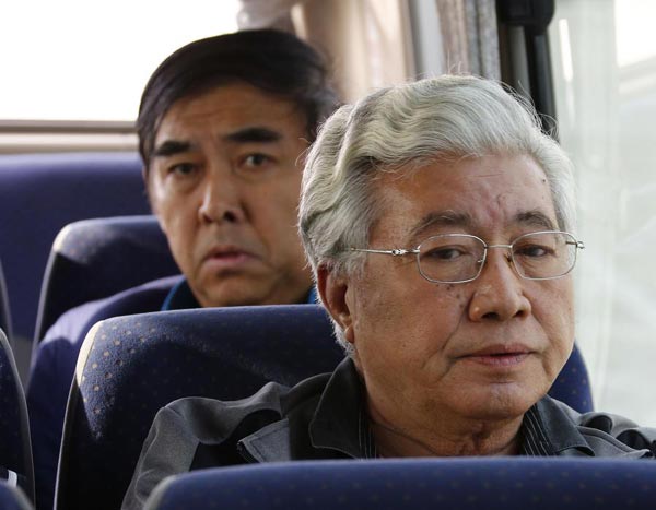Pang Shunxi, back, a former tax official of Tianjin municipality, and An Huimin, former general manager of a trade company in Tianjin, are escorted back to Beijing, March 28, 2015, after three months of exile in Laos. [Photo/Xinhua]