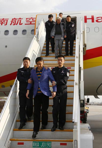 Pang Shunxi, front center, a former tax official of Tianjin municipality, and An Huimin, back center, former general manager of a trade company in Tianjin, are escorted back to Beijing, March 28, 2015, after three months of exile in Laos. [Photo/Xinhua] 