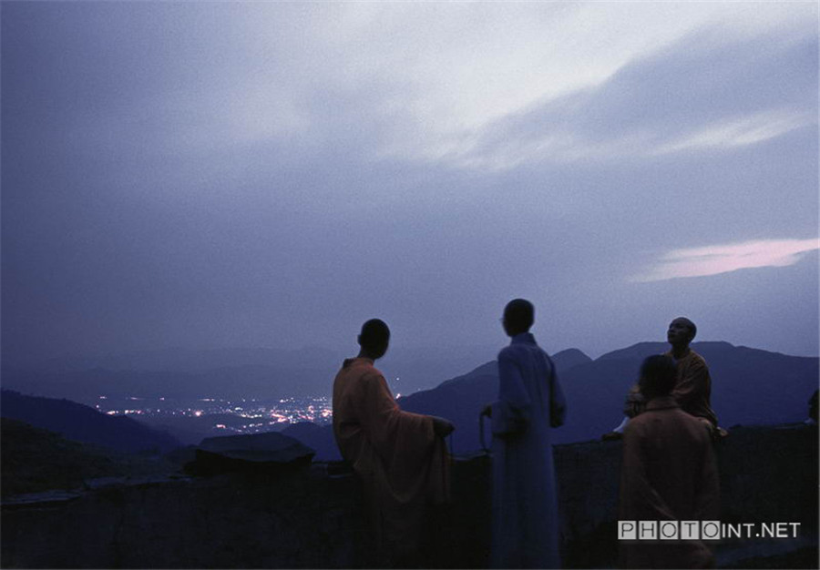 Human World. The student monks in the Buddhist Academy are watching the flickering lights of the town while walking in the evening. Even though some of them are really very young, they have left their homes, cut off the connections with their relatives, separated from the human world and settled down in the temples for all their lives. [Photo by Zhang Wang/photoint.net] 