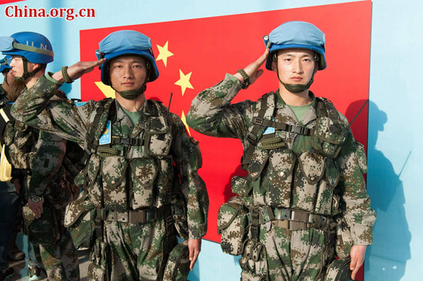 Two soldiers salute the Chinese national flag before boarding a plane headed to South Sudan for an eight-month U.N. peacekeeping mission. [Photo by Chen Boyuan / China.org.cn]