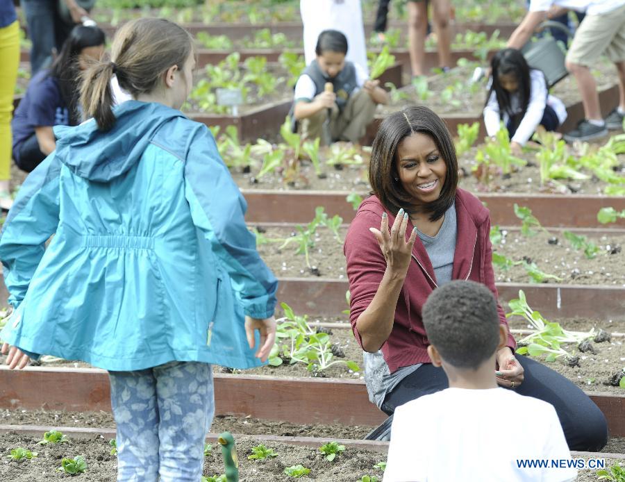 U.S. First Lady Michelle Obama plants with school children in the White House Kitchen Garden on the South Lawn of the White House in Washington D.C., capital of the United States, April 15, 2015. U.S. First Lady Michelle Obama joined FoodCorps leaders and local students to plant the White House Kitchen Garden for the seventh year in a row. [Photo/Xinhua]