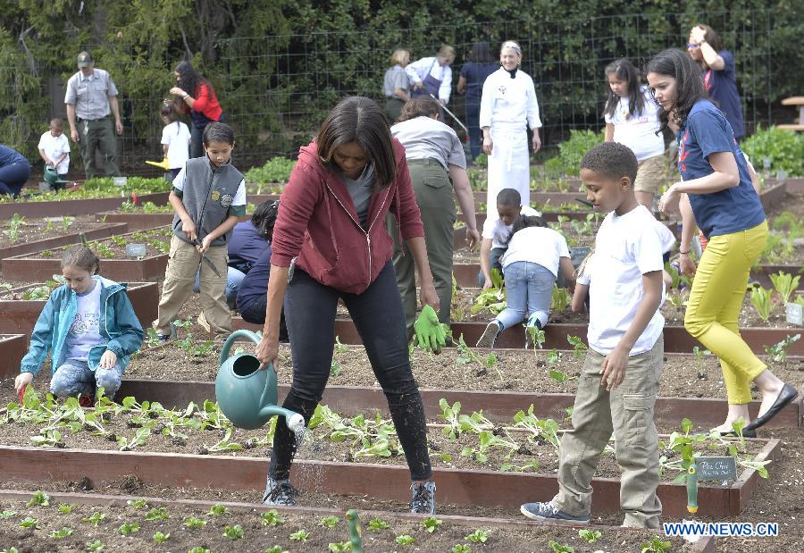 U.S. First Lady Michelle Obama(R) plants with school children in the White House Kitchen Garden on the South Lawn of the White House in Washington D.C., capital of the United States, April 15, 2015. U.S. First Lady Michelle Obama joined FoodCorps leaders and local students to plant the White House Kitchen Garden for the seventh year in a row. [Photo/Xinhua] 