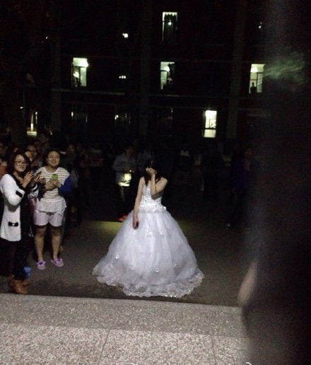 A photo from Sina Weibo user WMloveDX of a girl wearing a wedding gown waiting in front of a male student's dorm at Northwest University.[Photo/Sina Weibo] 