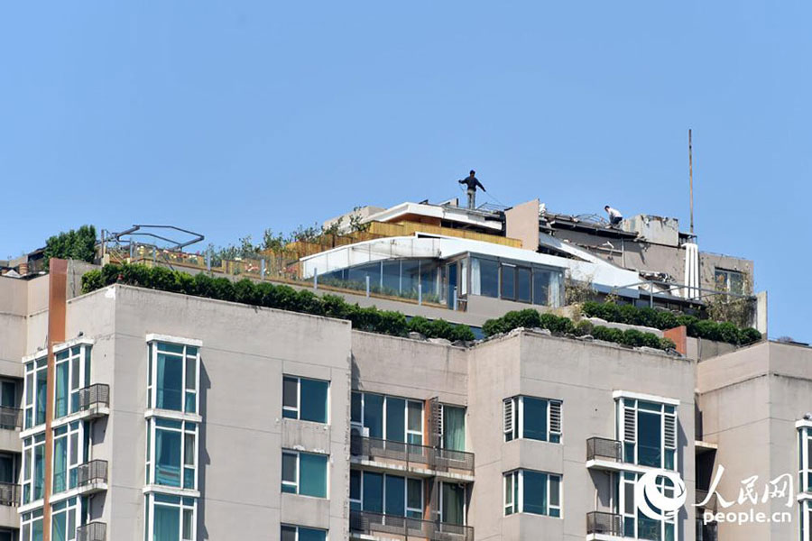 One-meter-tall bushes are seen atop a 26-story building in downtown Beijing on April 22, 2015. The building came into the spotlight two years ago, when it was discovered that a luxury illegal villa was built on its roof by a top-floor resident. Zhang Biqing, the man who had the villa built, tore it down when confronted by local law enforcement. [Photo: people.cn] 
