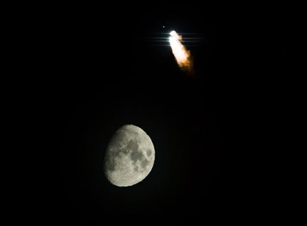 This March 30 file photo shows a Long March-3C rocket carrying a satellite, the 17th for the Beidou system, above the moon. [Photo: Xinhua]