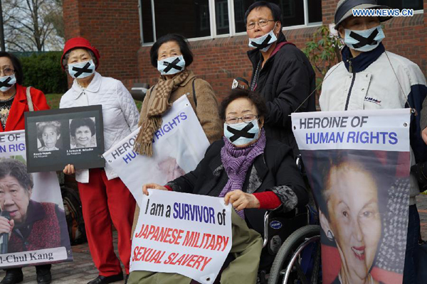Dozens of protesters hold signs and posters urging visiting Japanese Prime Minister Shinzo Abe to look squarely at history and apologize for the crimes committed by Japan during the World War II as Abe delivers a speech at the Harvard University in Cambridge, the United States, April 27, 2015. [Photo/Xinhua] 