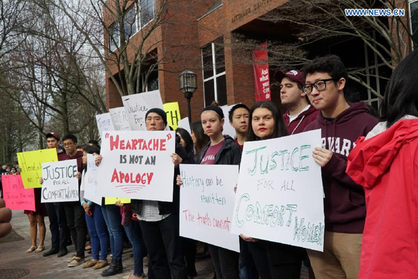 Dozens of protesters hold signs and posters urging visiting Japanese Prime Minister Shinzo Abe to look squarely at history and apologize for the crimes committed by Japan during the World War II as Abe delivers a speech at the Harvard University in Cambridge, the United States, April 27, 2015. [Photo/Xinhua]