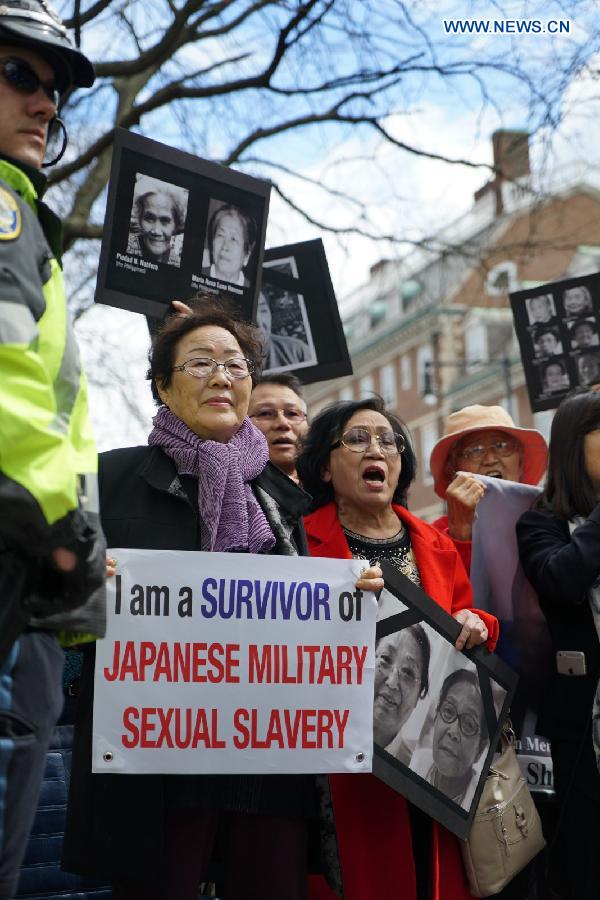 Dozens of protesters hold signs and posters urging visiting Japanese Prime Minister Shinzo Abe to look squarely at history and apologize for the crimes committed by Japan during the World War II as Abe delivers a speech at the Harvard University in Cambridge, the United States, April 27, 2015. [Photo/Xinhua]