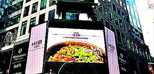 A photo of 'Reganmian', a kind of hot and dry noodles served with sesame paste, popular in Wuhan in Hubei Province, is shown on screen at Times Square in New York City on May 1, 2015. [Photo: Chutian Metropolis Daily] 