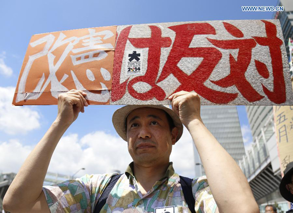 A man holds a placard during a demonstration for the protection of the Japan's pacifist Constitution in Yokohama, Japan, May 3, 2015. Some hundreds of people participated in the protest on Japan's Constitution Day. The effort of Japanese Prime Minister Shinzo Abe to emasculate and revise the country's war-renouncing constitution encountered a mass protest on Sunday, the country's 68th Constitution Memorial Day. [Photo/Xinhua]