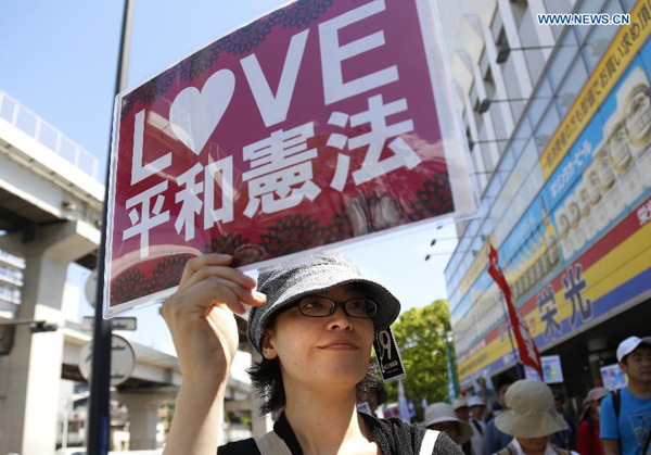 A woman holds a placard during a demonstration for the protection of the Japan's pacifist Constitution in Yokohama, Japan, May 3, 2015. Some hundreds of people participated in the protest on Japan's Constitution Day. [Photo/Xinhua]