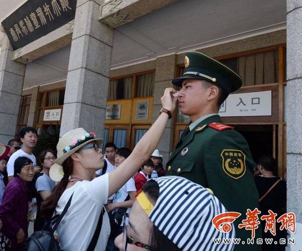 A tourist helps wiping the guard's sweat. [Photo/hsw.cn] 