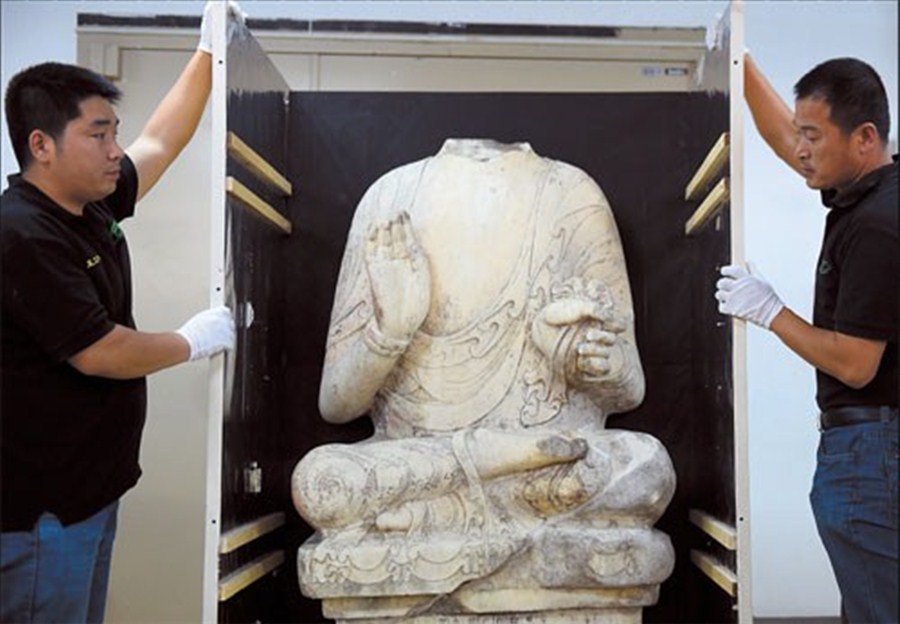 Workers check an ancient Buddhist sculpture at the Beijing World Art Museum yesterday before it is sent on to Kaohsiung in Taiwan where it will be reunited with its head during a cross- Strait exhibition. Its head was stolen in 1996 from the Youju Temple in Hebei Province. — Xinhua