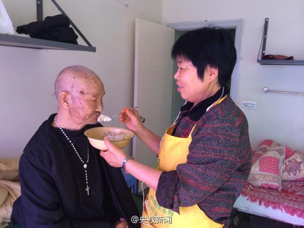 A 67-year-old retired doctor Wang Luji feeds an old man who lives in her nursing home in east China's Zhejiang province. [Photo: weibo.com]