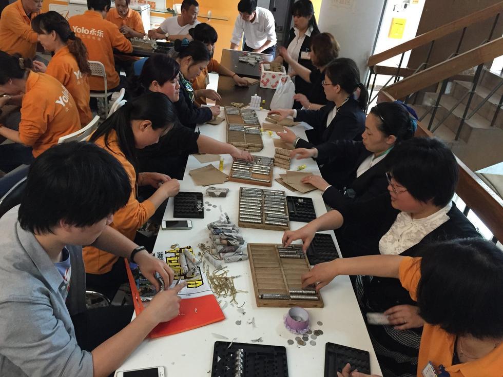 Bank employees count out the coins. Monks from Xingjue Temple carried more than 220,000 coins to a Shanghai mall to buy water heaters. The coins came from donations from pilgrims over many years. [China.org.cn]